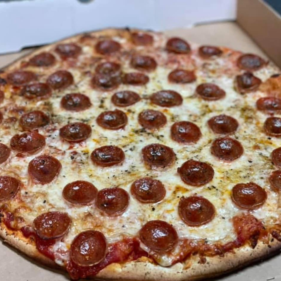 A close-up of a freshly baked pepperoni pizza from Lion's Den Pizzeria, in a cardboard box.
