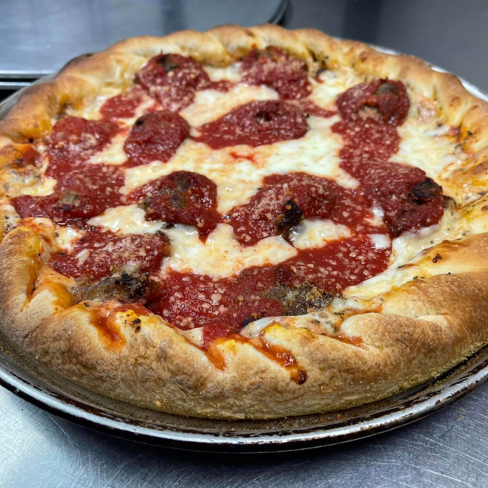 A deep-dish Lion's Den Pizzeria pizza with thick crust, melted cheese, and dollops of red sauce.