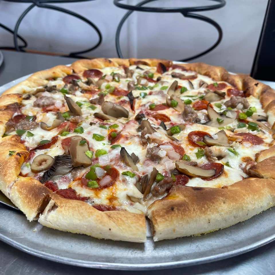 A freshly baked Lion's Den Pizzeria pizza with pepperoni, sausage, mushrooms, and green peppers.