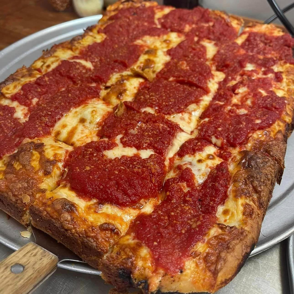 A rectangular Detroit-style pizza from Lion's Den Pizzeria, with thick red sauce and melted cheese.